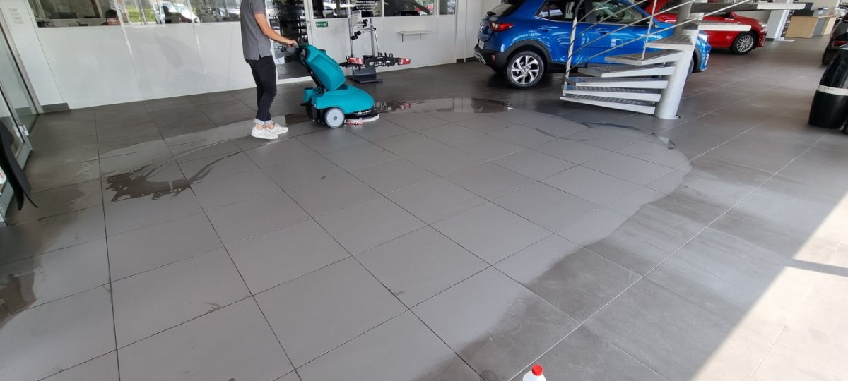 Nettoyage d'un sol en grès cérame dans un showroom avec une autolaveuse équipée d'un disque mélamine
